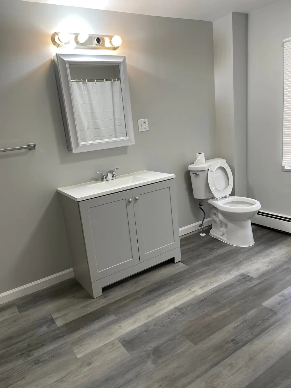Renovated bathroom with new vanity, mirror and luxury vinyl flooring