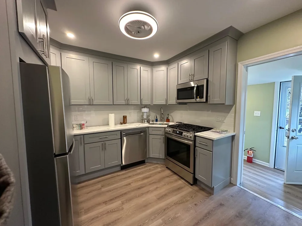 Renovated gray shaker kitchen with stainless steel appliances and luxury vinyl flooring