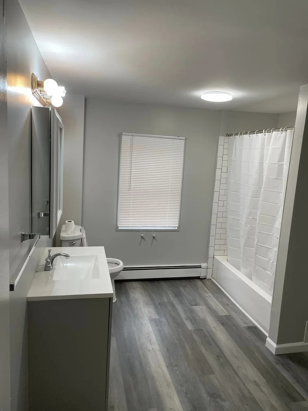 Renovated bathroom with subway tile tub surround and new vanity