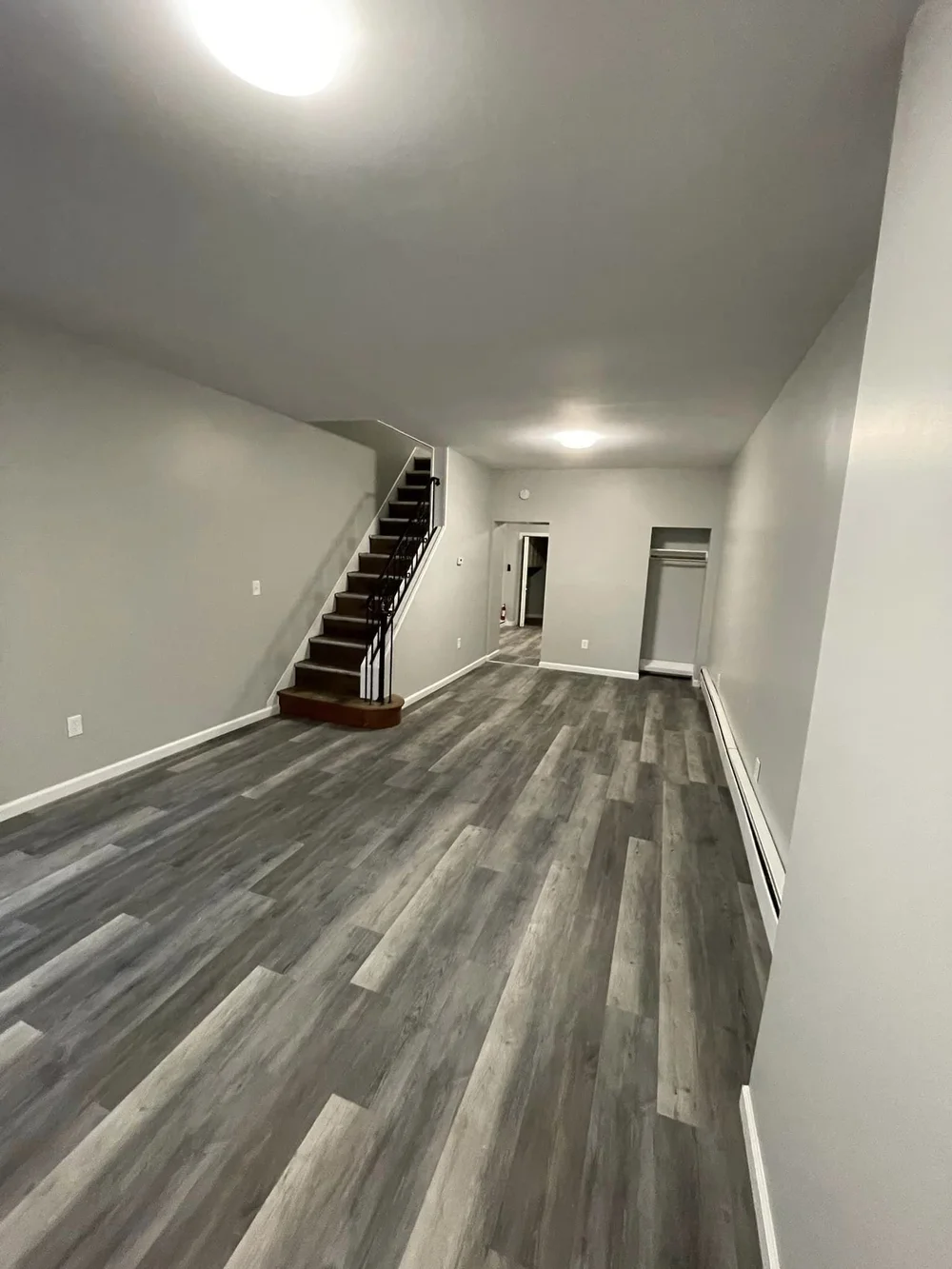 Finished basement living space with luxury vinyl plank flooring and staircase